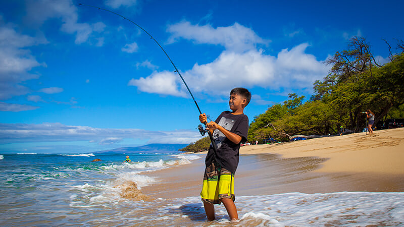 A boy fishing from a beach