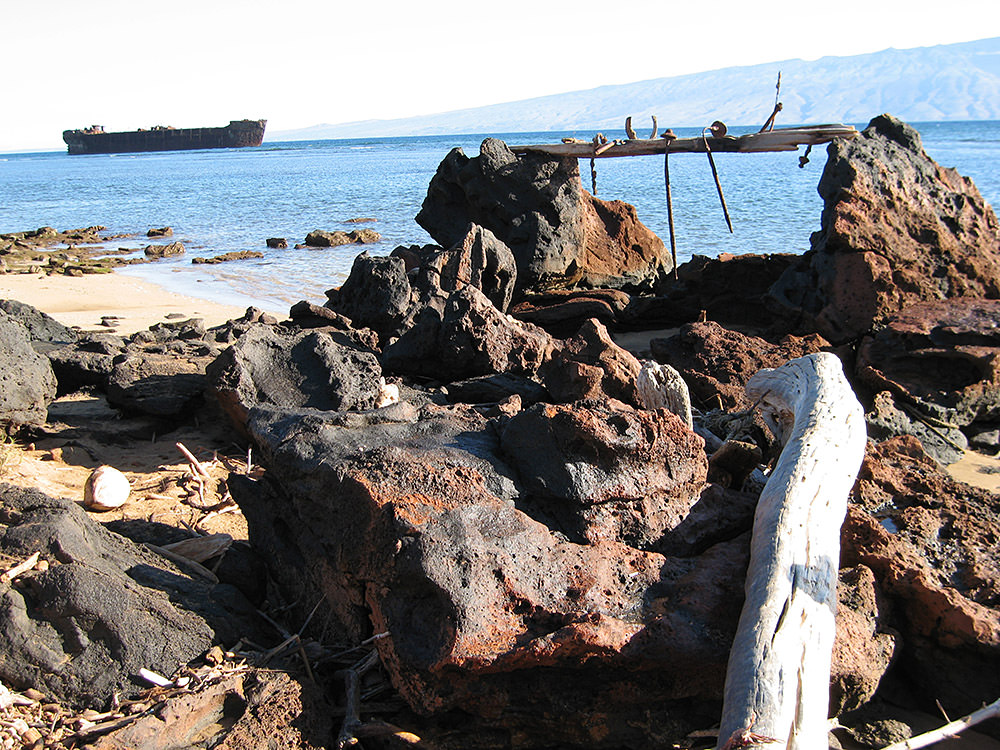 view of a shipwreck from a beach covered in rocks