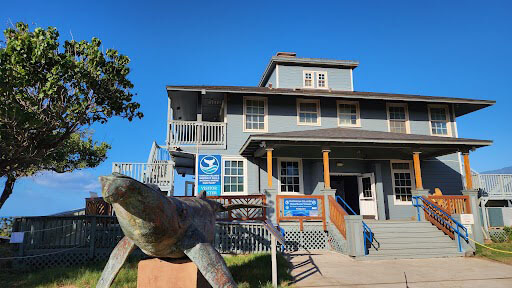 A blue building with a humpback whale statue in front